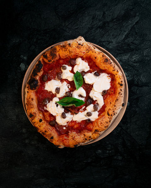 Pizza mit Tomatensauce, Käse und Basilikumblättern auf dunklem Hintergrund.