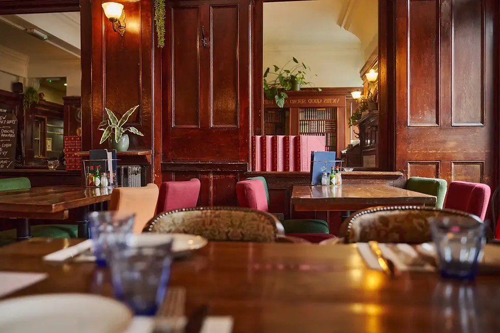 Cosy seating area inside The Somers Town Coffee House with wooden tables, colourful chairs and tradi