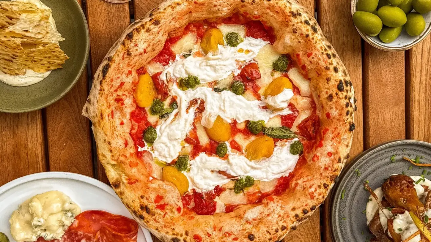 Crust Bros 2.0 Margherita pizza with mozzarella, tomatoes, basil pesto, and parmesan.