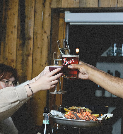 Friends raise glasses in a toast over a seafood sharing platter during a celebration at Cosy.