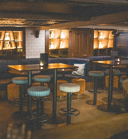 Tables and booth seating inside Cosy, arranged and ready for guests in the intimate basement bar.