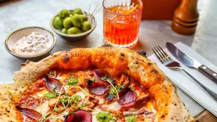 Butter Chicken Pizza served with cucumber raita, olives and a cocktail.