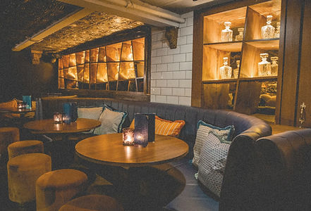 Comfortable booth seating and softly lit tables inside Cosy Cocktails, creating an intimate lounge setting for cocktails and conversation.