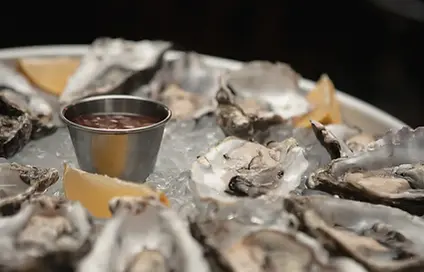 Fresh oysters served on crushed ice with lemon wedges and a mignonette dipping sauce.
