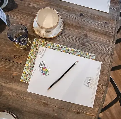 Notebook, pencil and coffee on a wooden table set up for hot desking at The Somers Town Coffee House.