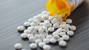 Spilled white pills from an orange prescription bottle on a dark table, with Northeast Radio SD logo and text.