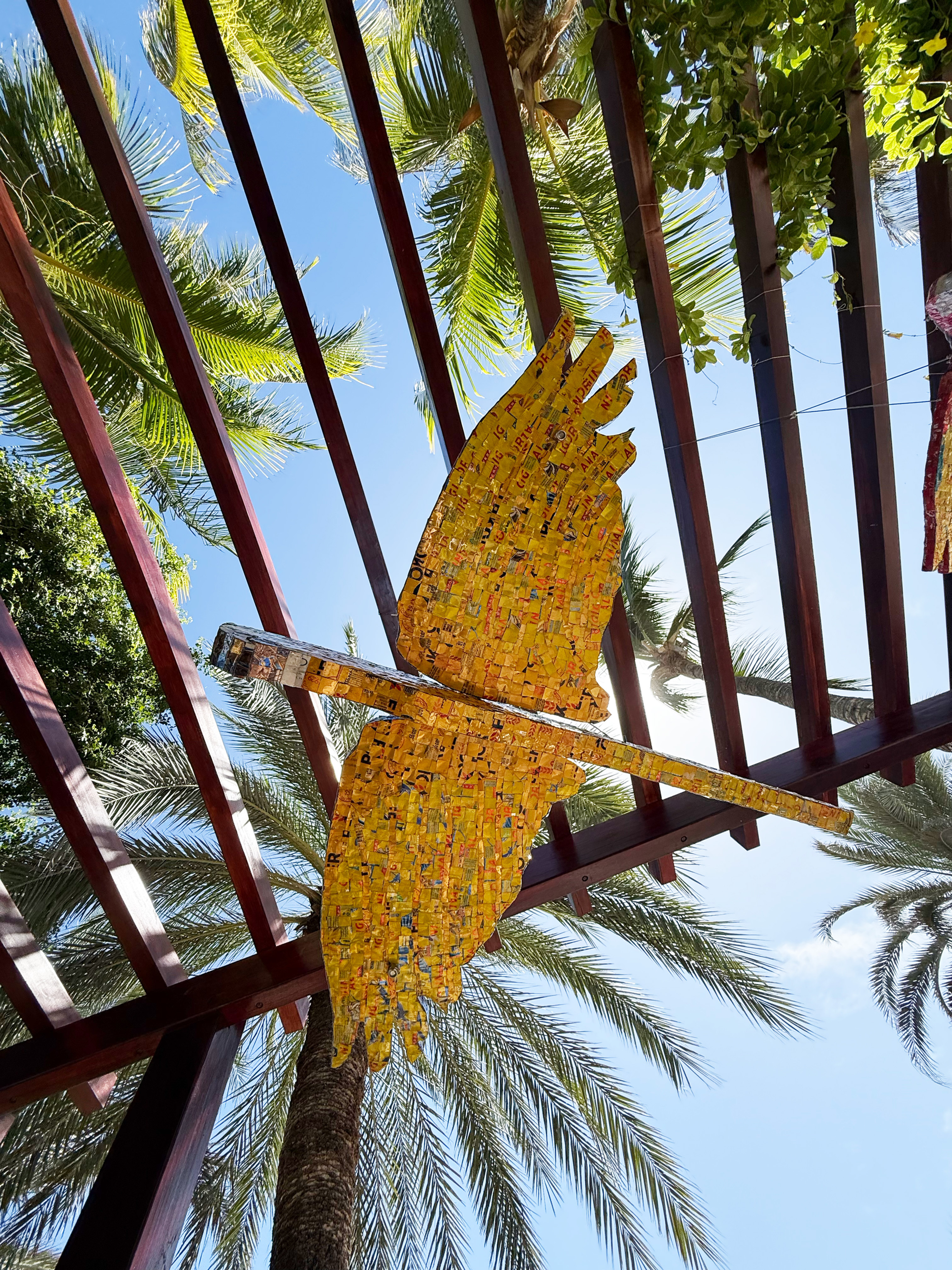 Guacamayo decorativo amarillo bajo pérgola.