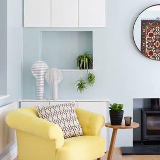 Un fauteuil vert d'eau dans un séjour au mur bleu pastel