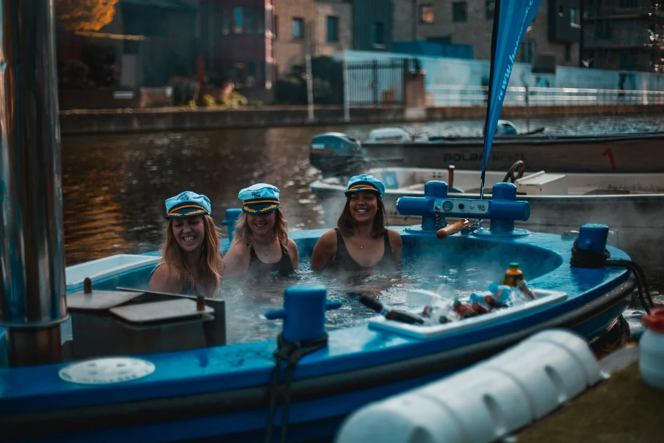 People relaxing in a Skuna Boats hot tub boat in Canary Wharf, London, combining sightseeing with a floating spa experience.