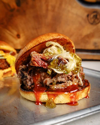 A juicy burger with a bun and toppings, freshly prepared and displayed on a table at Cue Point.