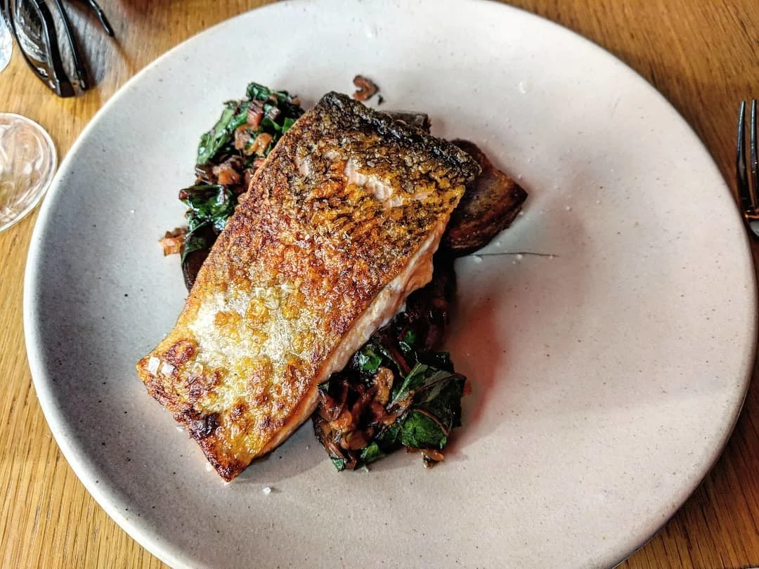 A beautifully plated dish of grilled fish with greens, served at Artusi - Peckham & Soho.