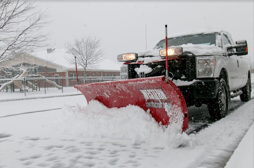Landscape photo of a white pickup truck with a red snow plow clearing a snowy driveway in a residential area