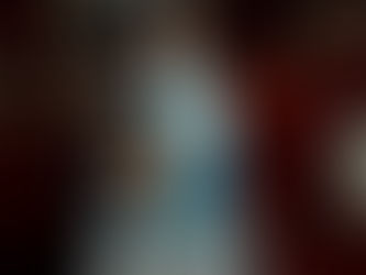 A man with glasses and mustache carries a smiling child on his shoulders in a cozy kitchen, red cabinets in background, cheerful mood.