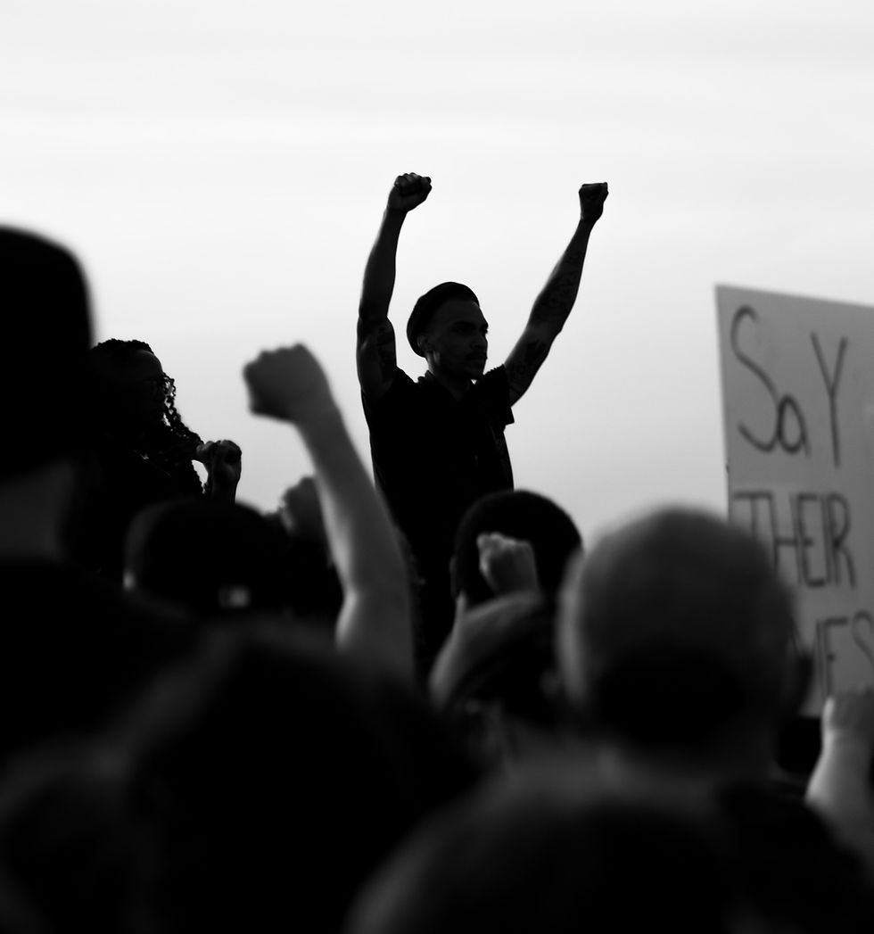 Black and white image of man with upraised arms in protest