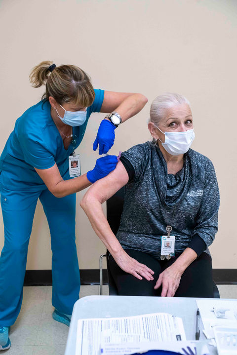 An elderly woman receiving an injection from a healthcare worker
