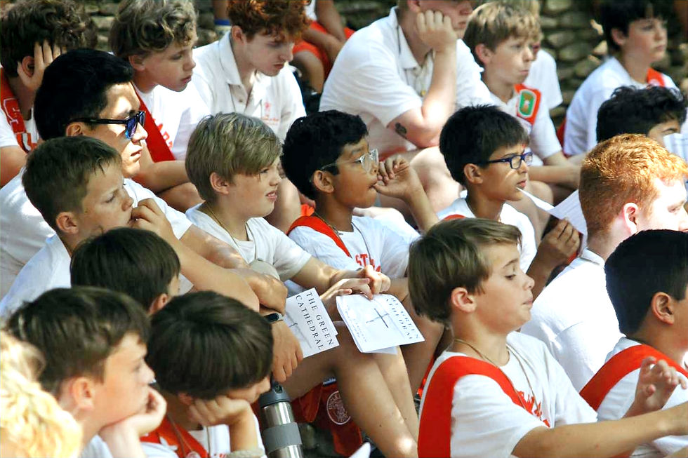 Boys wearing Camp Stewart uniforms sitting outdoors at a worship service.