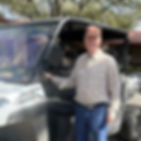 A man wearing a trucker hat standing next to a truck.