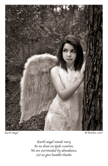 A sepia photo of a young woman with feathered wings leaning against a tree
