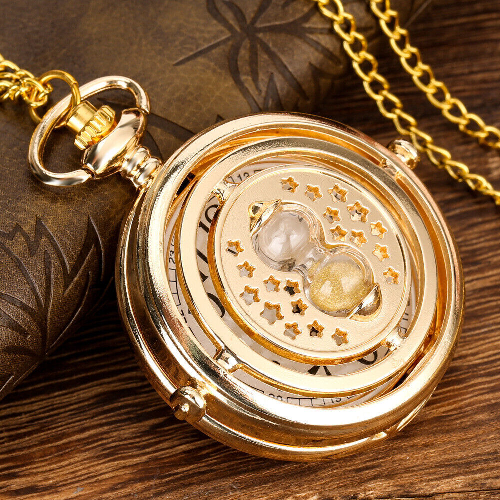 Golden pocket watch with decorative face and chain on a wooden surface.