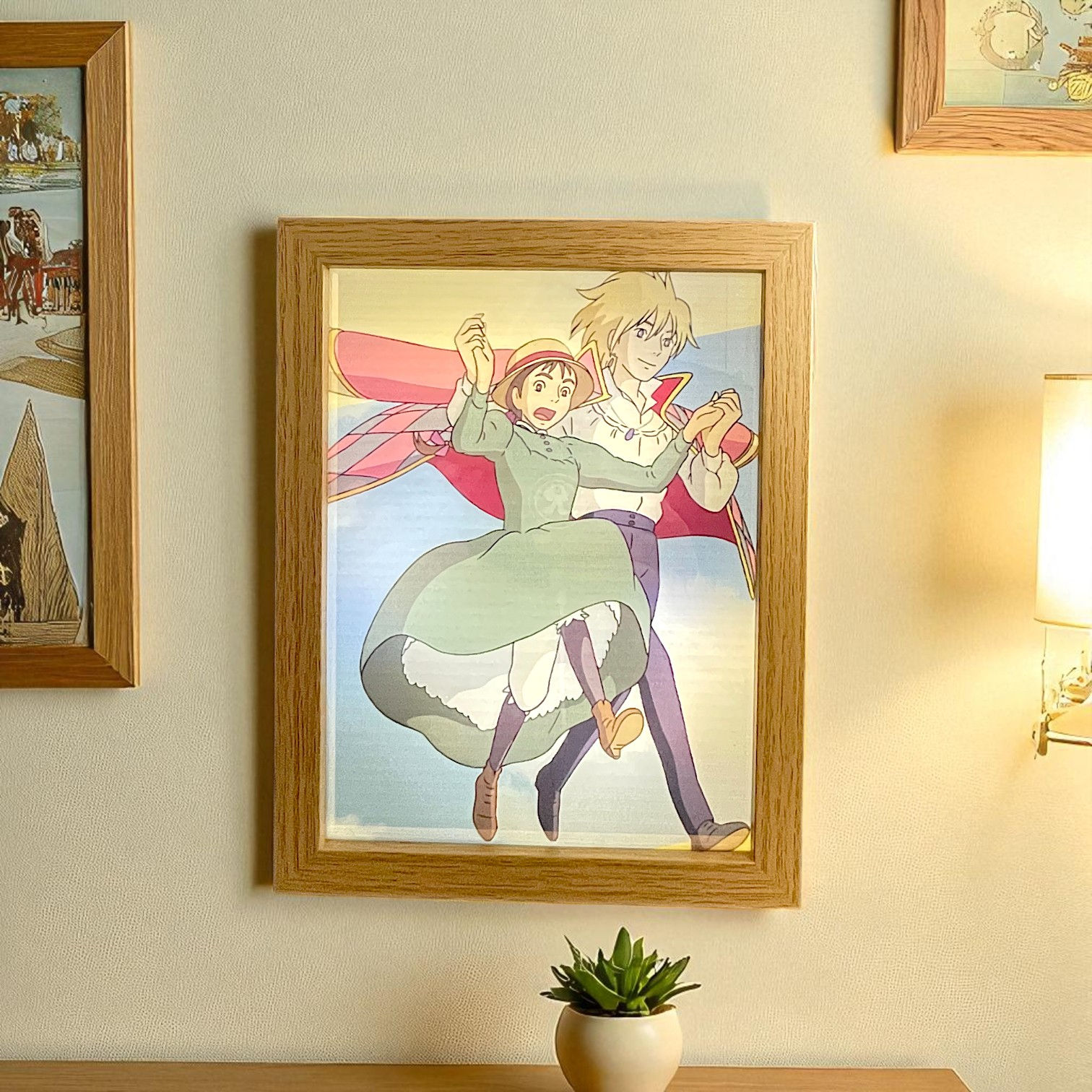 Anime characters dancing in a wooden frame on a white wall; art prints.