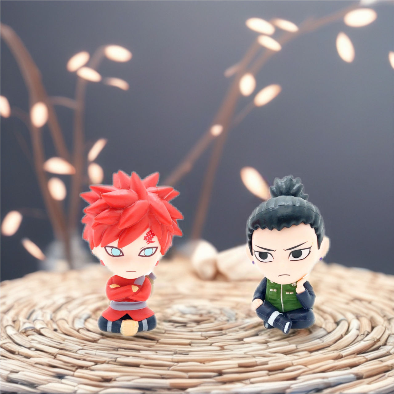 Two anime figures, a red-haired Gaara and Shikamaru, sitting on a woven mat.