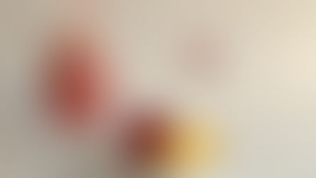 A pink strawberry milkshake in a tall glass with a striped straw. A bowl of strawberries and vanilla ice cream sits nearby.