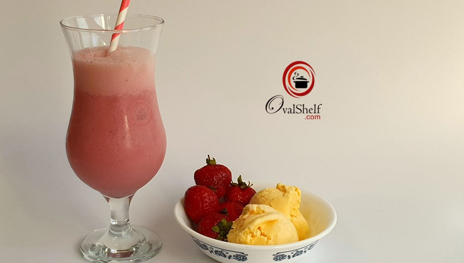 A pink strawberry milkshake in a tall glass with a striped straw. A bowl of strawberries and vanilla ice cream sits nearby. 