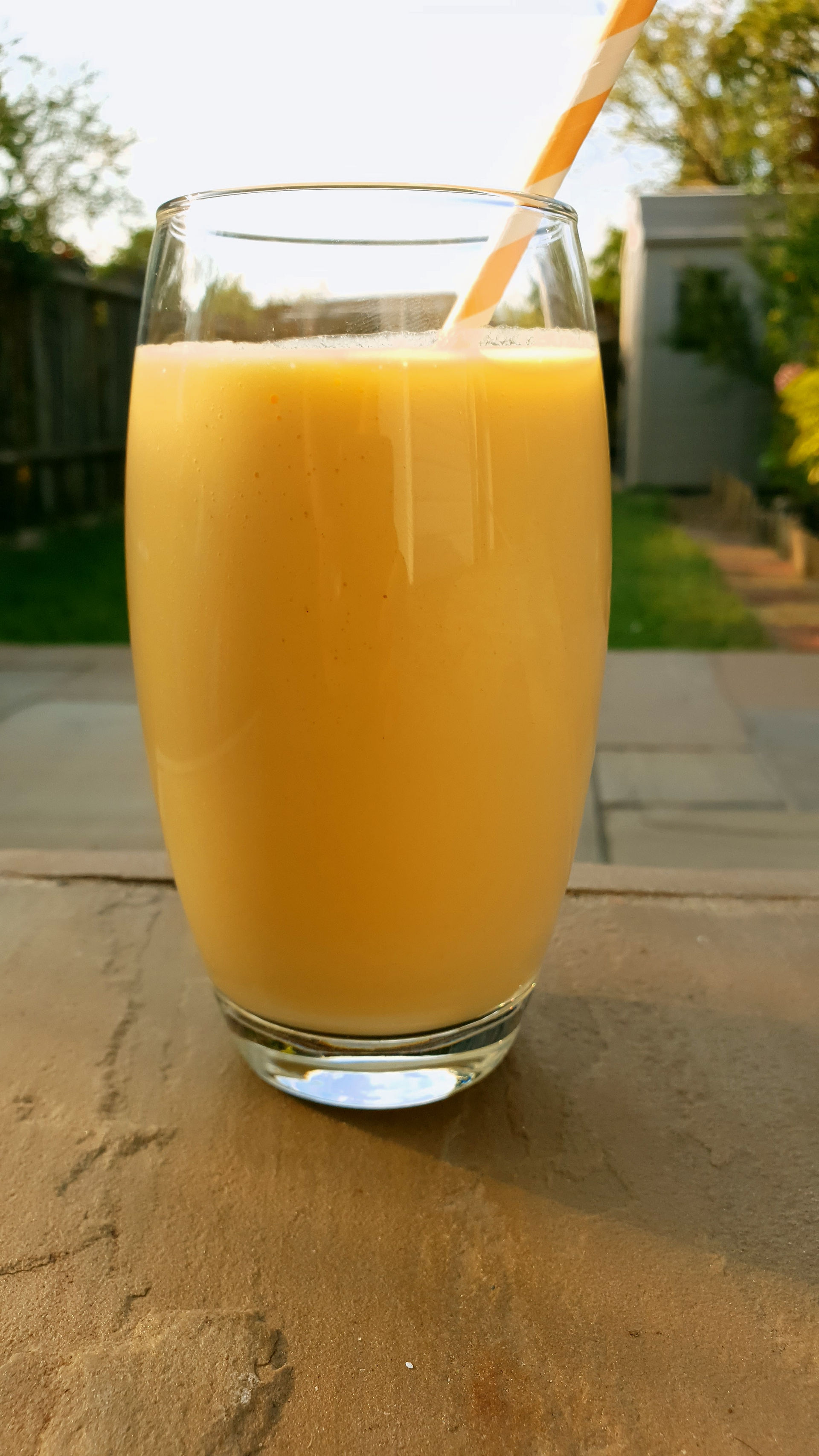 Mango Milkshake in a tall glass with a straw in it