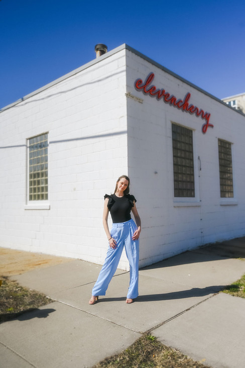 young female high school graduate posing for her senior pictures in downtown Des Moines, Iowa wearing blue pants and a black top
