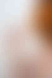 female high school senior with red hair posing in studio with white background wearing pearls and a warm floral dress