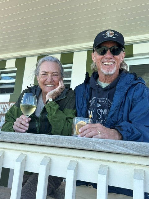 Peter C. Guild and his wife on a deck drinking wine.