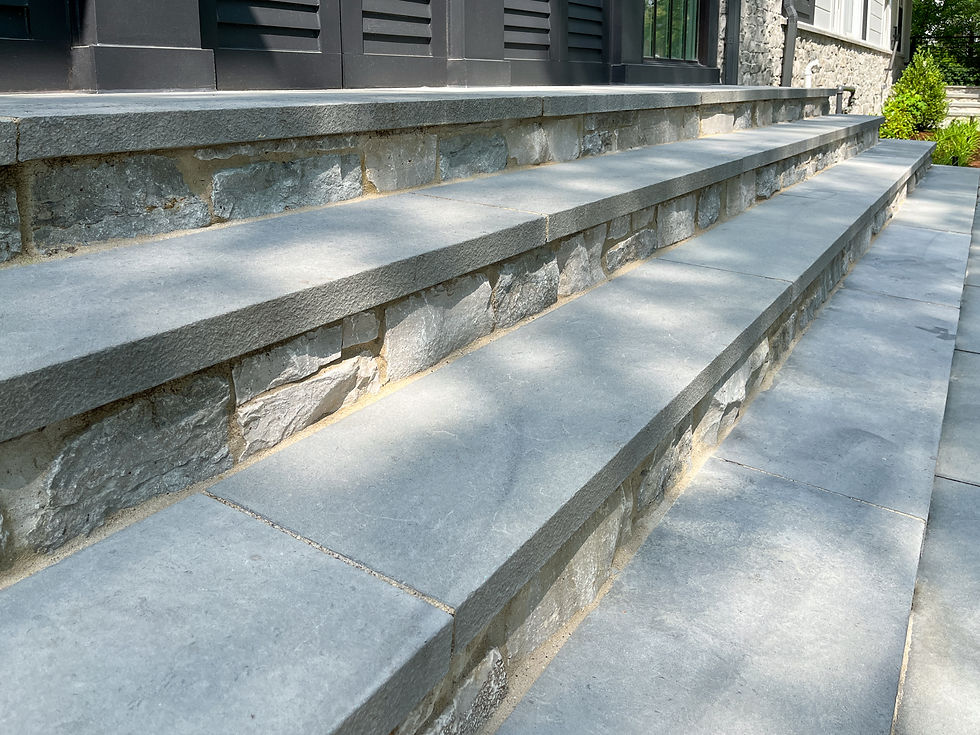 Italian Bluestone 2" thick stair treads cap three steps veneered with a chiseled ledgestone cut natural stone veneer in grey