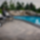 An outdoor pool with teal blue water. The pool deck made out of Belgard Dimensions concrete pavers.