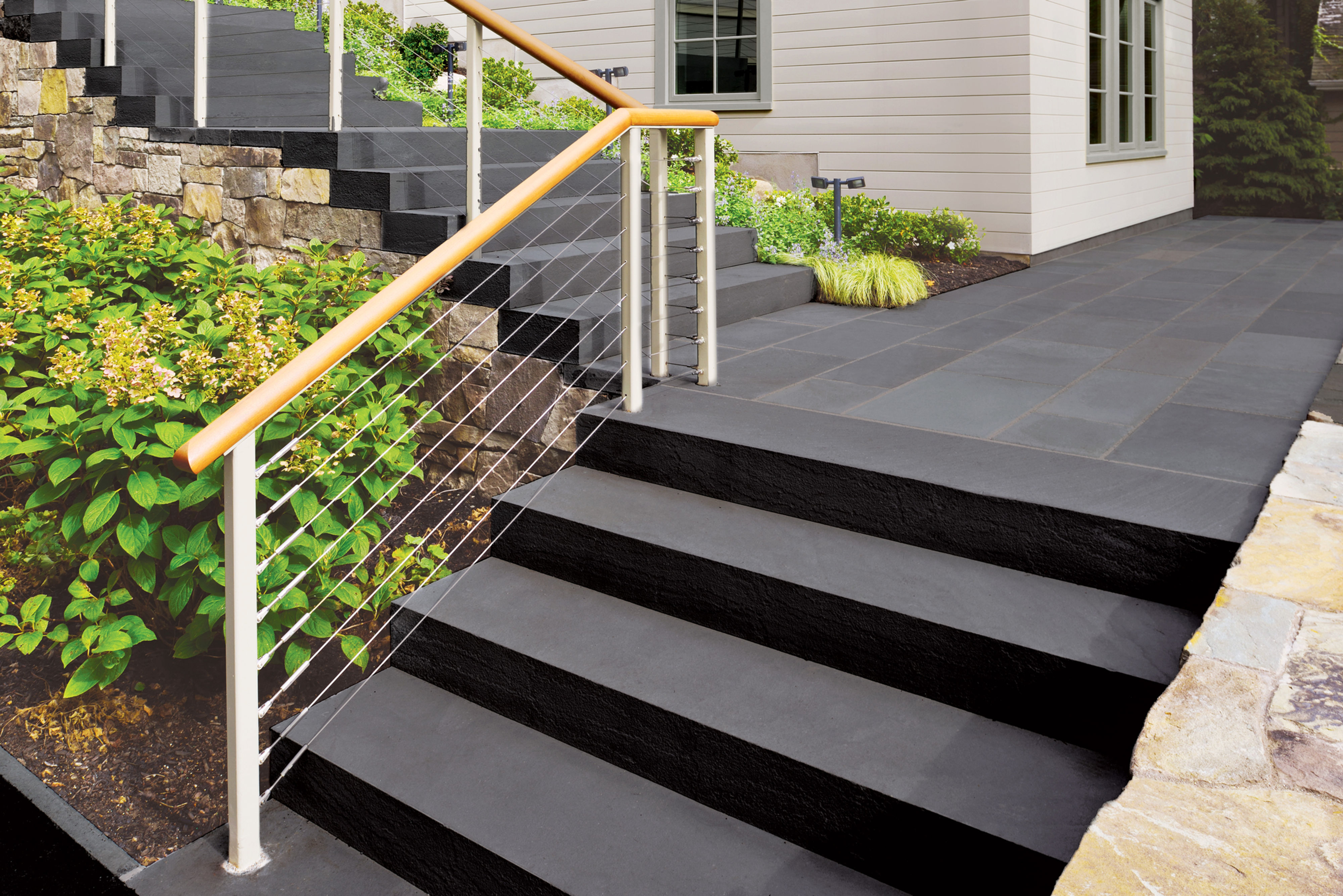 Outdoor steps leading up to a landing all made out of natural premium dark bluestone treads and pattern.