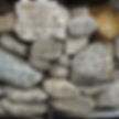 A crate of natural beach round stone in small to medium sized boulders. Smooth finish with light  greys, tans, and whites.