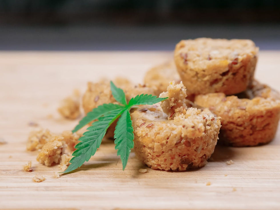 Cookies, cannabis edibles, scattered on a wooden surface with a green cannabis leaf on top. Blurred background creates a calm, natural setting.