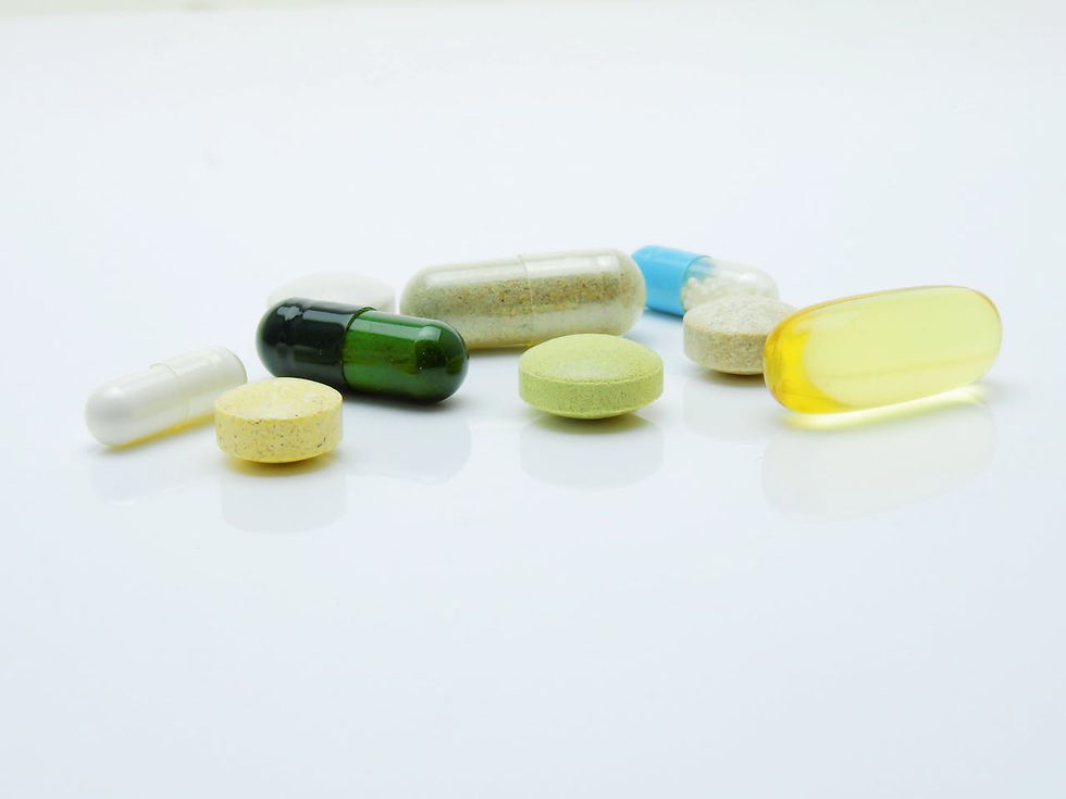 A variety of colorful pills and capsules are scattered on a white surface, including yellow, green, and clear ones, reflecting a bright mood.