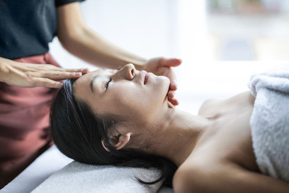 A woman receives a relaxing head massage in a bright room, eyes closed, wrapped in a white towel. Calm and soothing atmosphere.