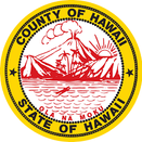 County of Hawaiʻi seal. Yellow circle with black font reading "County of Hawaii" over the top and "State of Hawaii" circling the bottom. Within the circle in red ink is a land and sea-scape with a large erupting volcano, a smaller volcano to the left, and the ocean with an outrigger canoe in the forefront. Sun shines over the right mountain range. The words OLA NA MOKU circle the bottom of the picture in red.