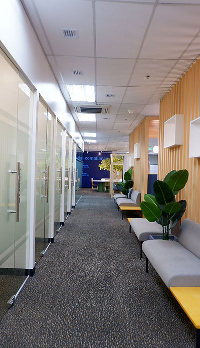 An office interior space of a long corridor and a selection of couches