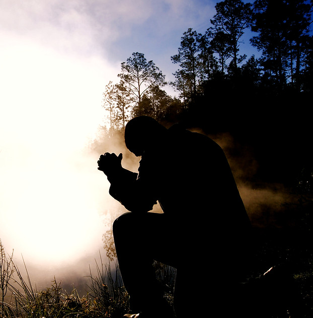 Silhouette of a person praying outside