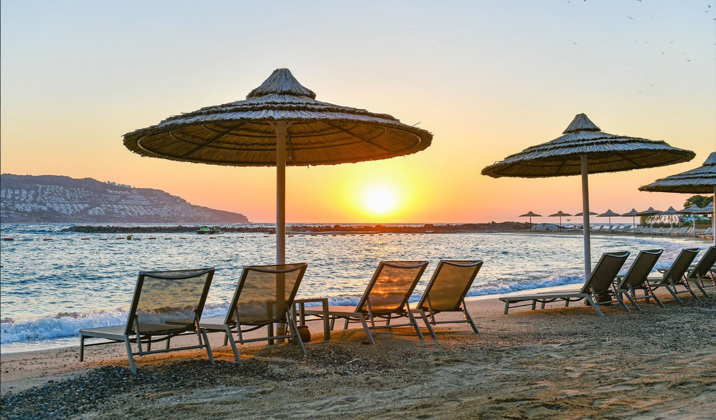Sunset view with beach loungers and umbrellas by the sea in Bodrum.