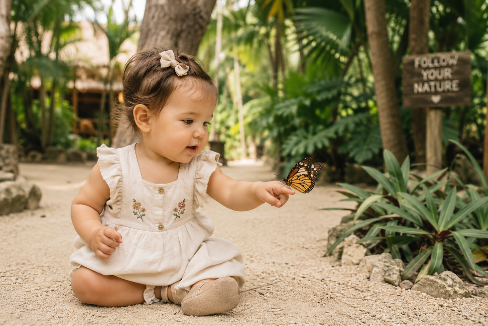 Una bebé de un año realiza una actividad en el parque mirando una mariposa.