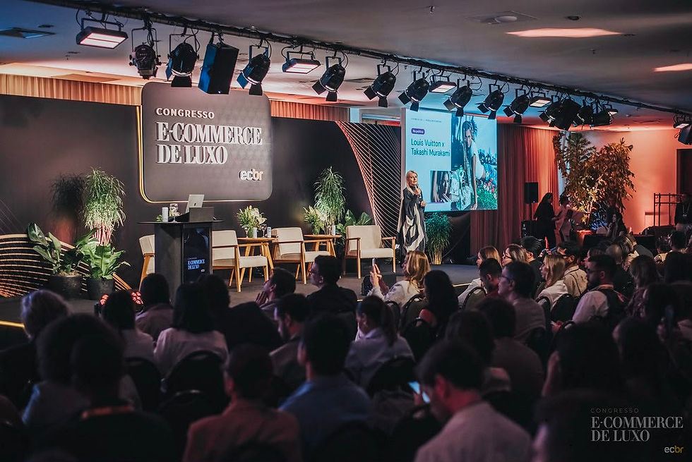 Congresso E-commerce de Luxo em auditório, palestrante no palco diante de público; tela mostra Louis Vuitton x Takashi Murakami.