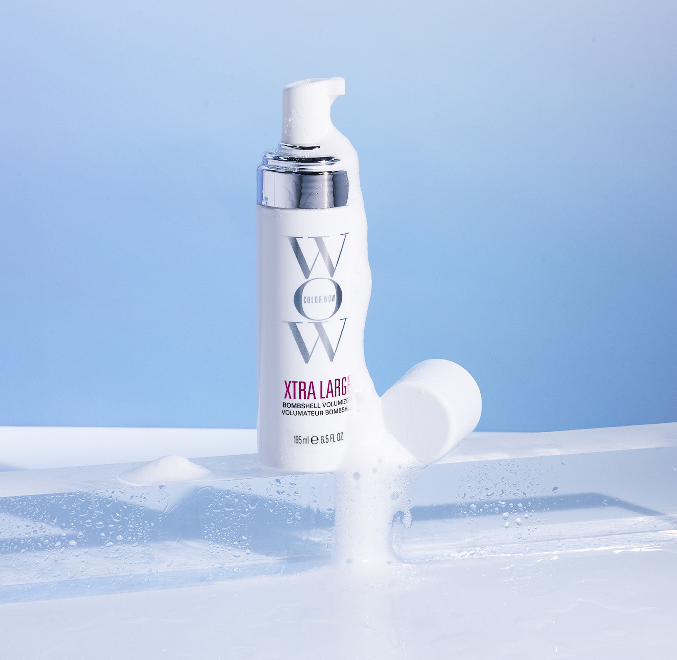 Frasco branco de mousse capilar WOW Xtra Large sobre bloco de gelo, com espuma derramando e fundo azul claro.