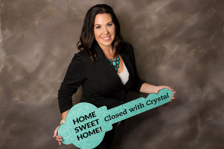 Professional headshot of Crystal Cardenas, broker and team leader of Team Cardenas Real Estate Group, holding teal key sign