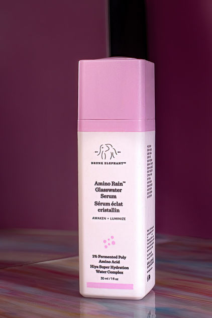 Luxury product photo of Drunk Elephant Amino Rain Glasswater Serum against a purple backdrop with clean studio lighting.