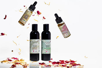 Luxury product photography of My Natural Butter skincare oils and body butters floating with dried rose and calendula petals on a clean white background by Dawn V Gilmore VIP Photo.