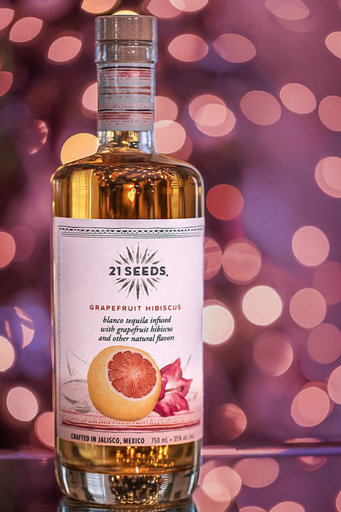 21 Seeds grapefruit hibiscus tequila bottle photographed in studio with pink and purple lighting