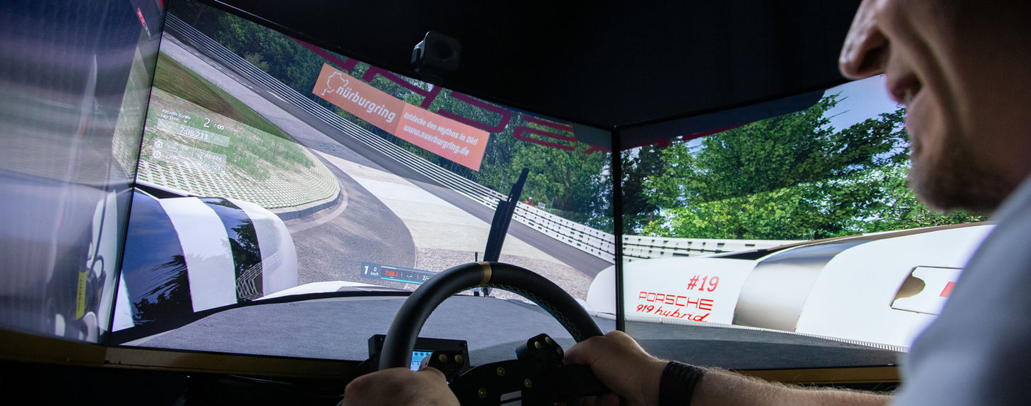 Mann nutzt Rennsimulator mit Lenkrad und Panorama-Display